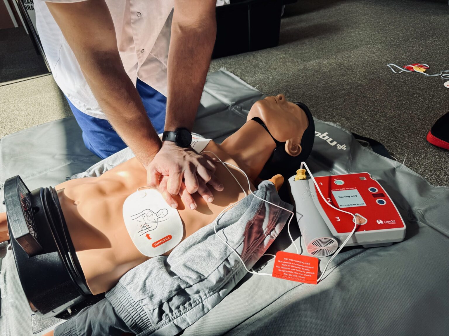 Exercice de massage cardiaque avec défibrillateur lors d’une formation premiers secours Alertis