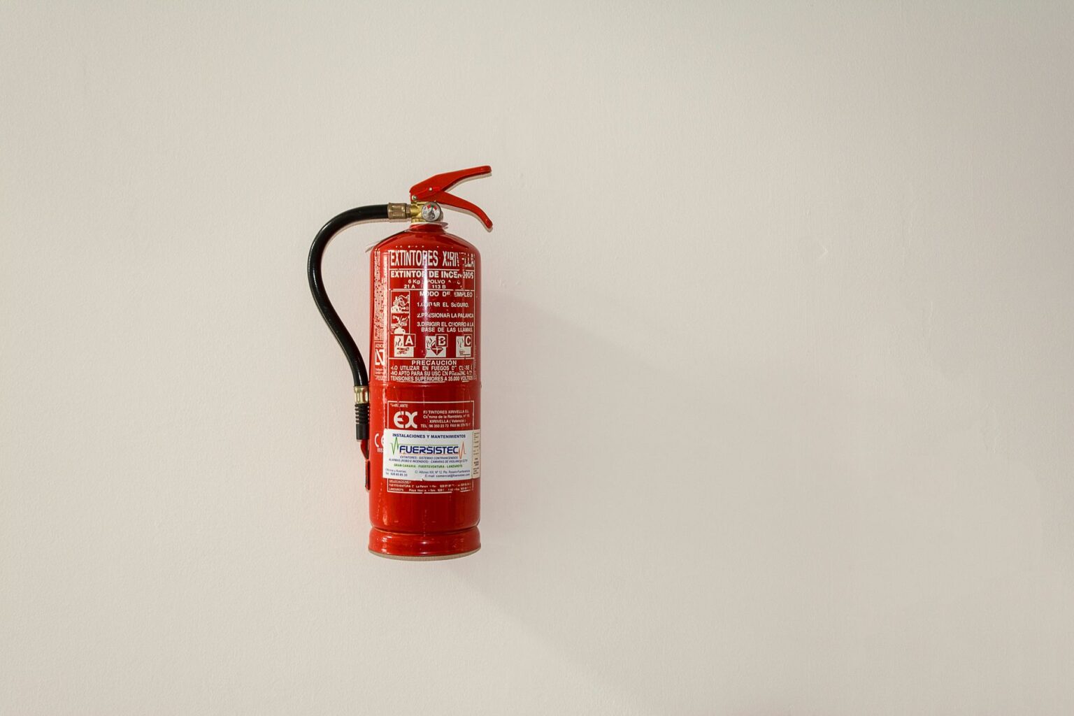 Extincteur neuf posé sur un mur clair