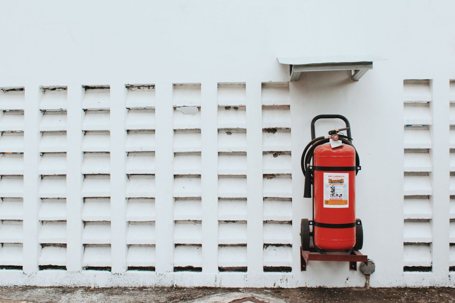 Extincteur à poudre fixé sur un mur clair